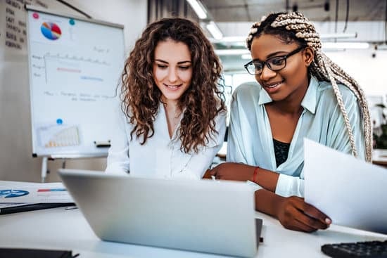 Duas mulheres sorridentes trabalhando em frente ao computador